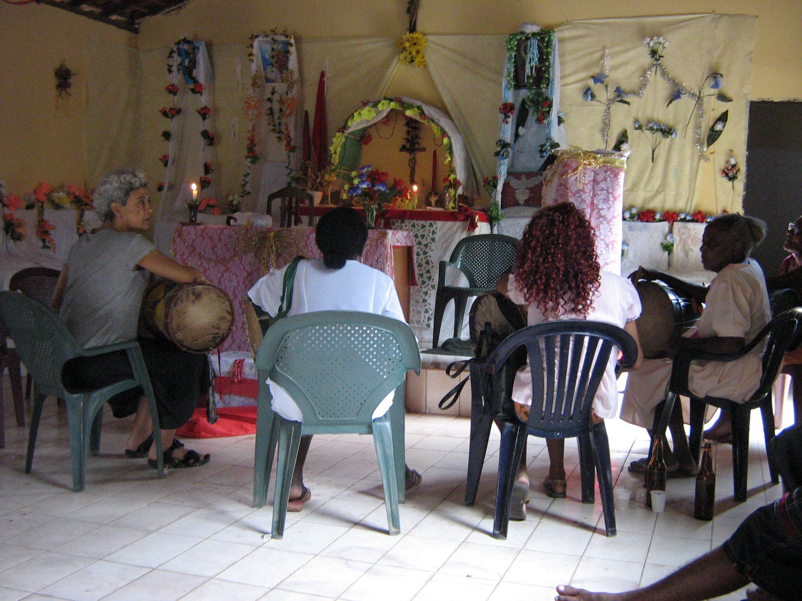 Fotografia de Caixeiras tocando em frente ao altar do Divino no quilombo Santa Rosa dos Pretos em Itapecuru Mirim no Maranhão. À direita está Severina Pires Belfort que foi grande Caixeira do quilombo. 2010.