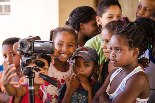 Crianças observam o processo de gravação da visita de Mestras e Mestres à sua escola na Maiadinha, onde foram brincar a dança do Boilé e contar e ouvir histórias com as crianças.
                  Território Kalunga do Vão do Moleque