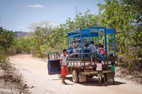 Na saída da escola na Maiadinha, no Vão do Moleque, as crianças sobem na carroceria da caminhonete que tem grades de proteção ao redor e que as transporta para casa depois das aulas. O motorista acompanha atento.